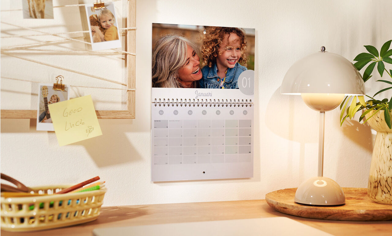 Un calendrier accroché au mur avec des photos personnelles et un design épuré. Une pièce joliment aménagée.