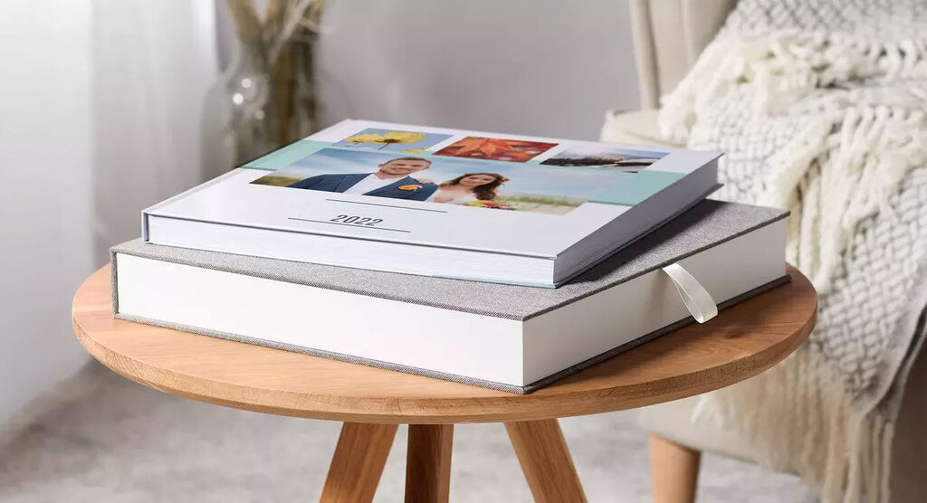 Deux CEWE Albums photo sur un plateau en bois, l'un empilé sur l'autre, décoré avec des photos préférées.