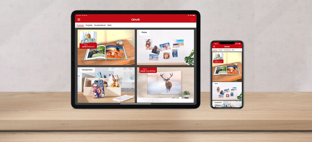 Deux appareils affichent le logiciel CEWE Photos avec divers produits photo sur une table en bois.