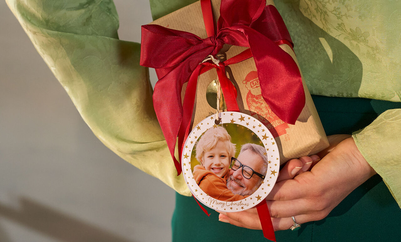 Une personne tient un cadeau délicatement emballé avec un ruban rouge.