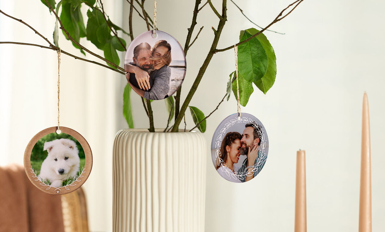 Trois images rondes suspendues à une branche décorative dans un vase.