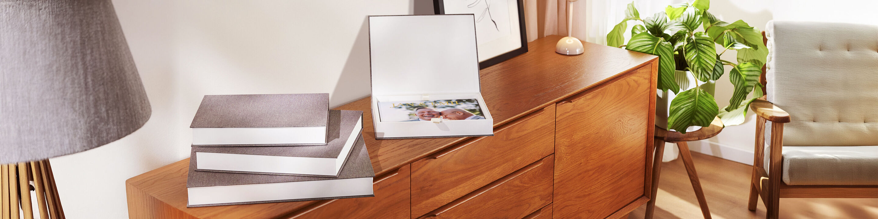 Trois beaux albums photo dans un salon lumineux sur un meuble en bois.