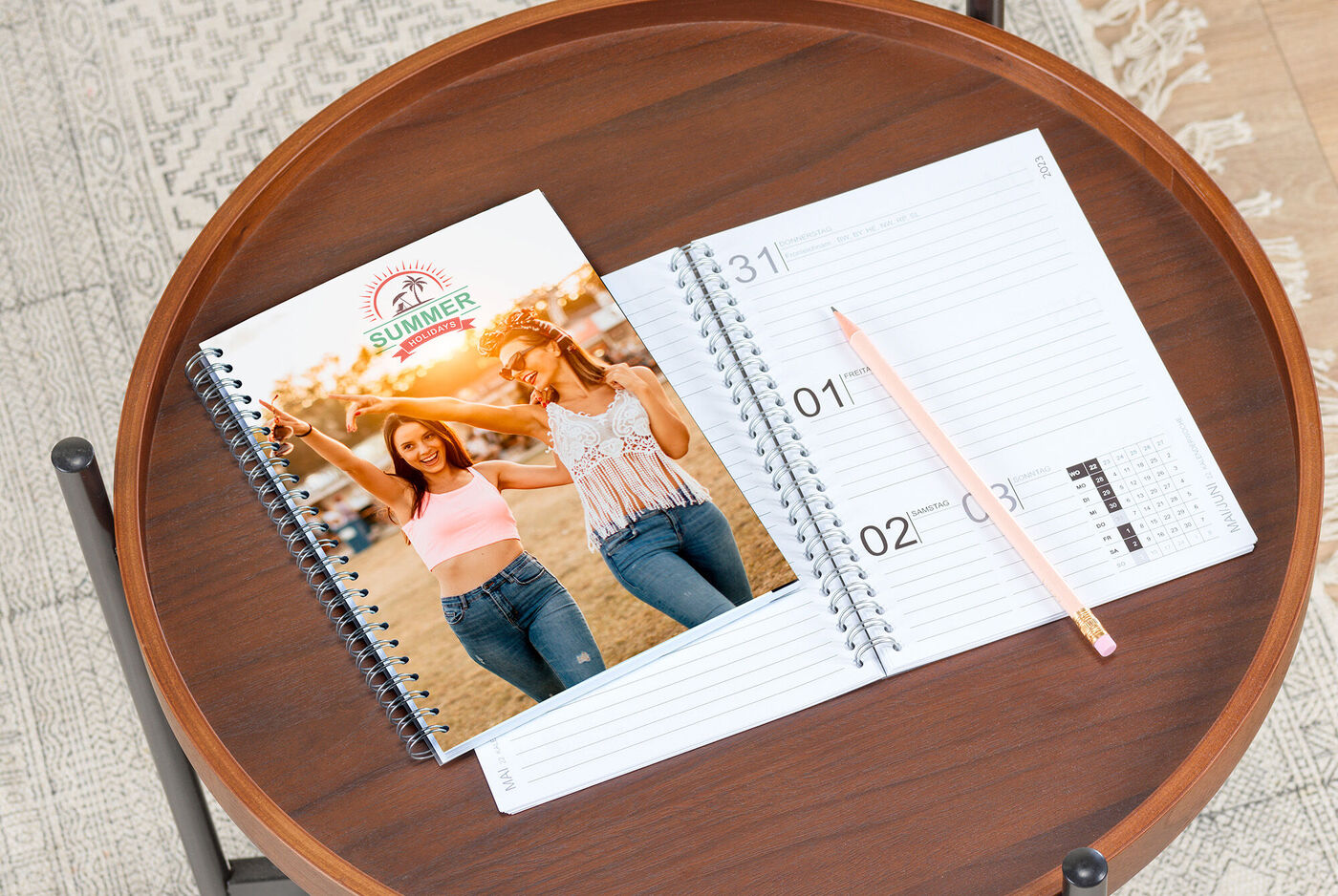 Un livre photo CEWE posé sur une table à côté d'un carnet vide et d'un crayon