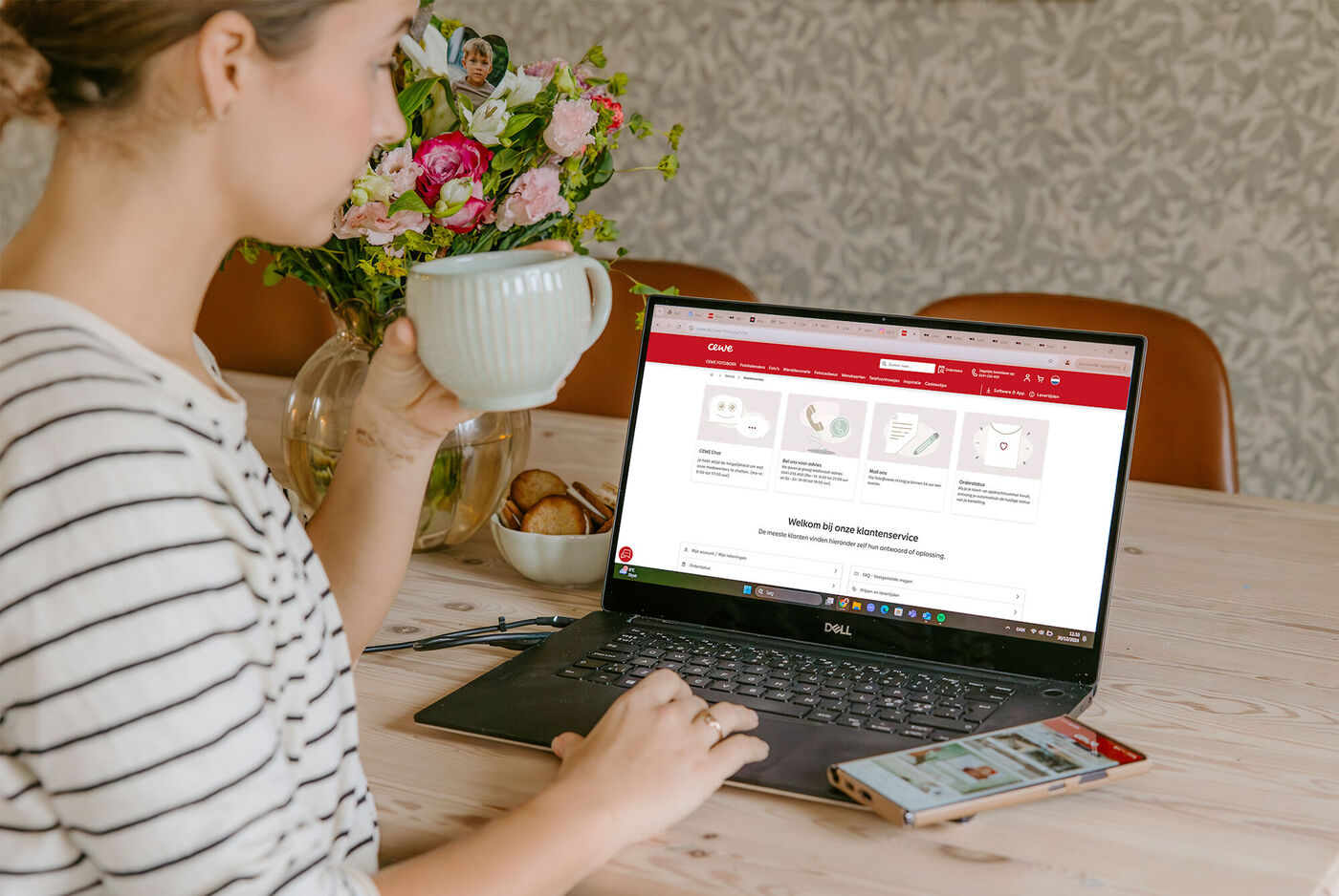Une personne est assise à une table avec un ordinateur portable et une tasse.