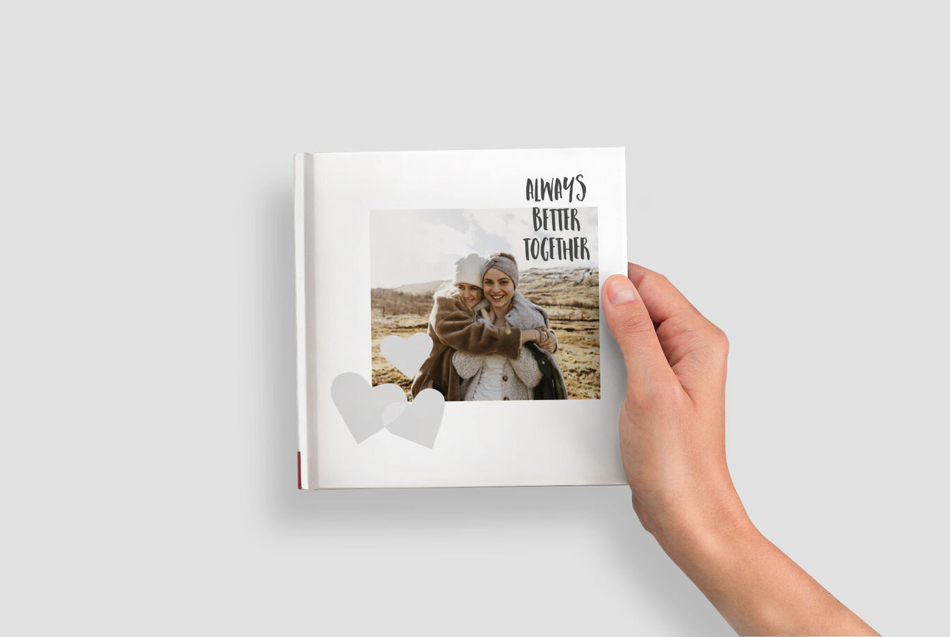 Une main tient un album photo ouvert avec une image et une couverture annotée.