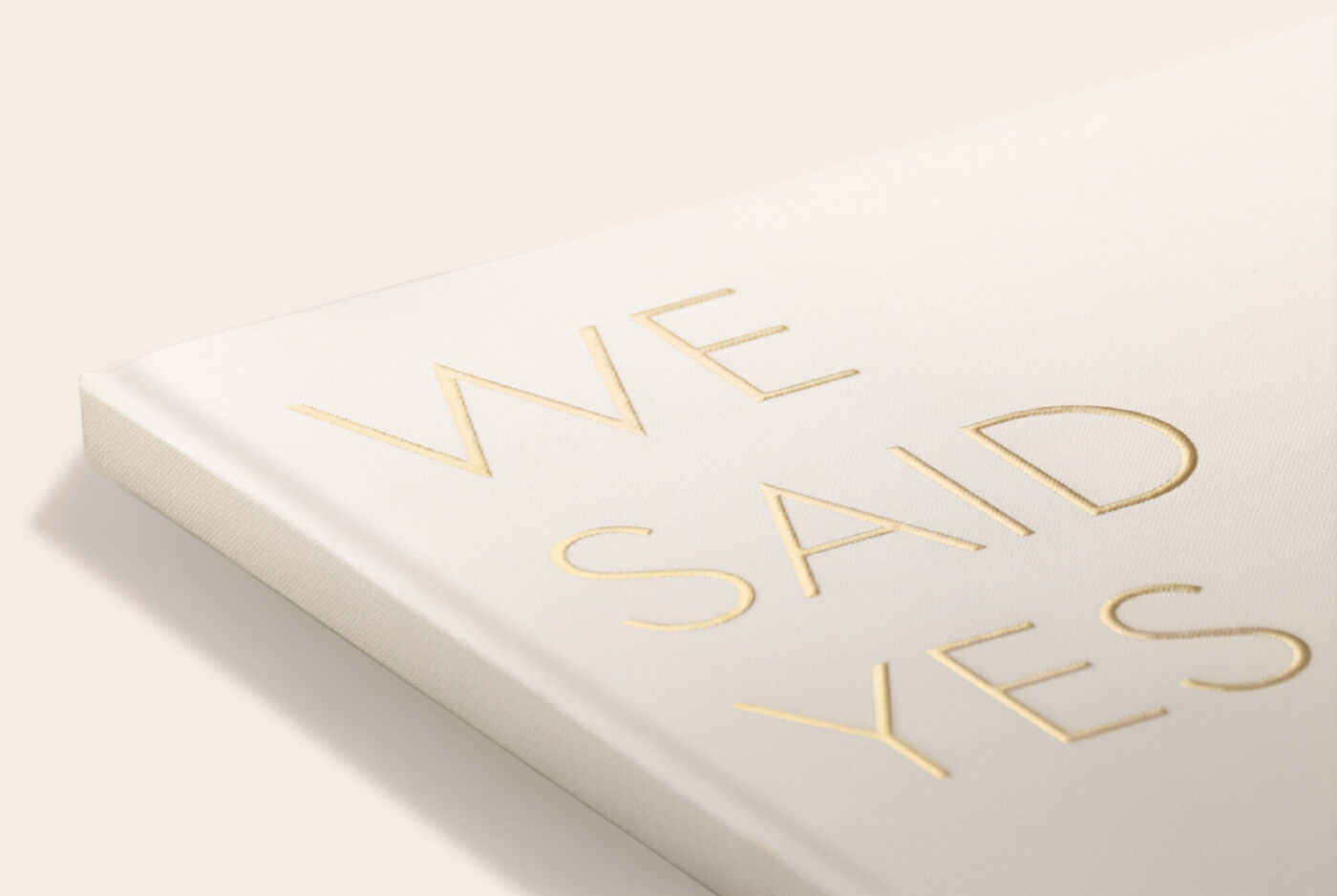 Livre photo avec une couverture blanche et les lettres dorées « WE SAID YES ».