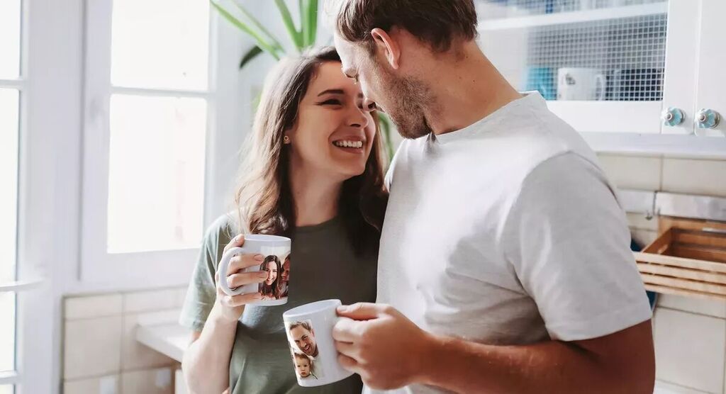 Couple dans cuisine claire appréciant café avec tasses perso.