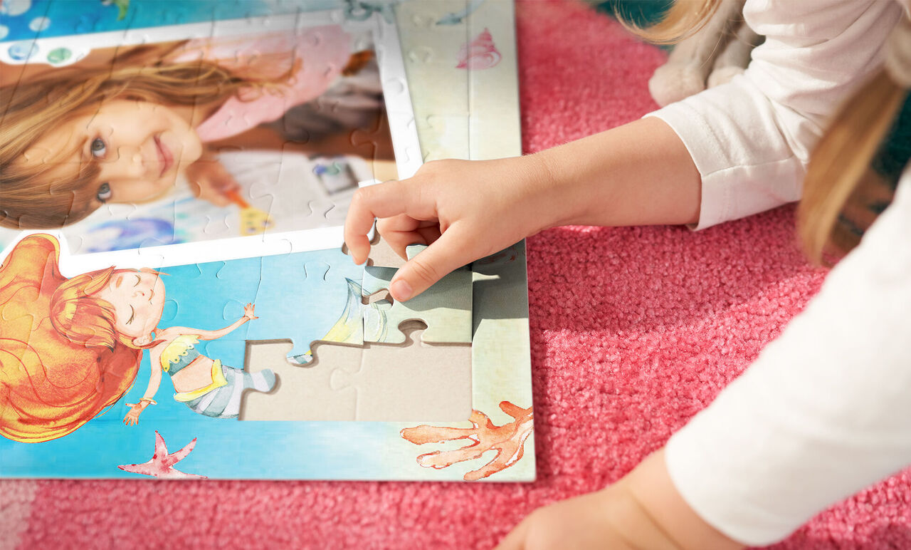 Un enfant est allongé sur un tapis rose et insère une pièce d'un puzzle coloré avec des créatures marines.