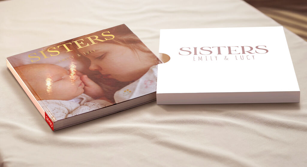 Un CEWE Livre photo "Sisters" ouvert sur une table, avec deux sœurs en couverture.