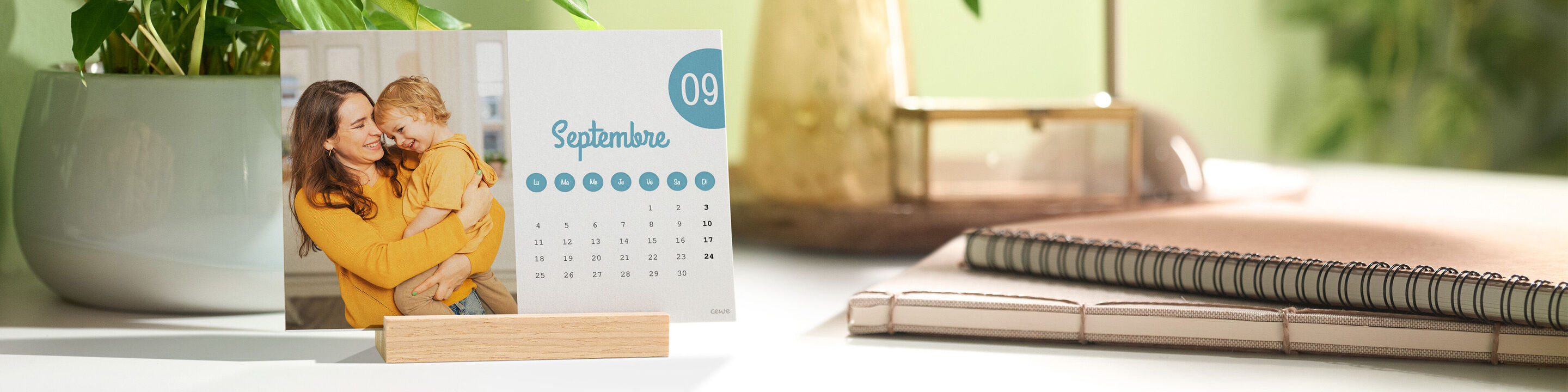 Un calendrier de bureau avec une photo d'une mère et son enfant est posé sur un bureau dans un support en bois.