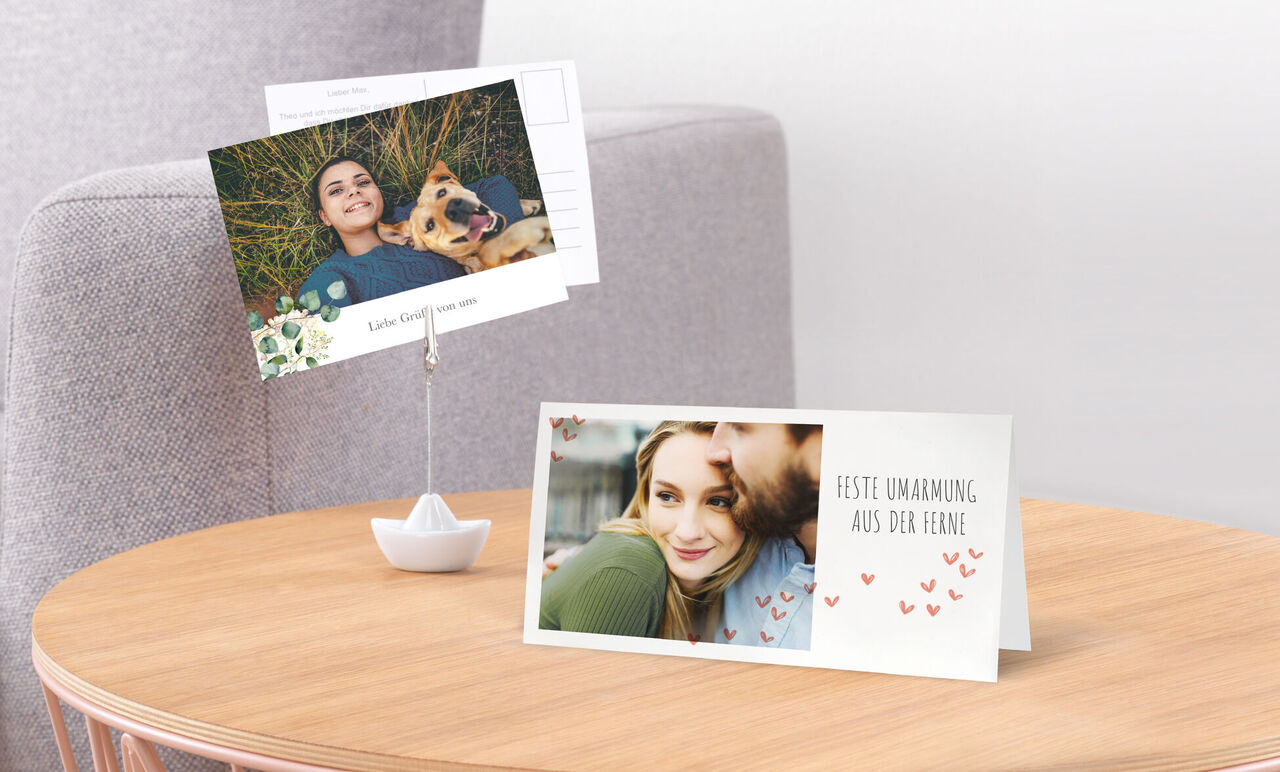 Deux cartes de vœux soigneusement conçues sur une table. Une carte montre une étreinte romantique, l'autre un chien à l'extérieur.
