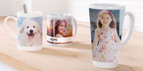 Trois tasses avec des impressions photo individuelles sur un bureau en bois. Une tasse montre un chien, une autre une fille en robe fleurie et la troisième a un fond coloré.