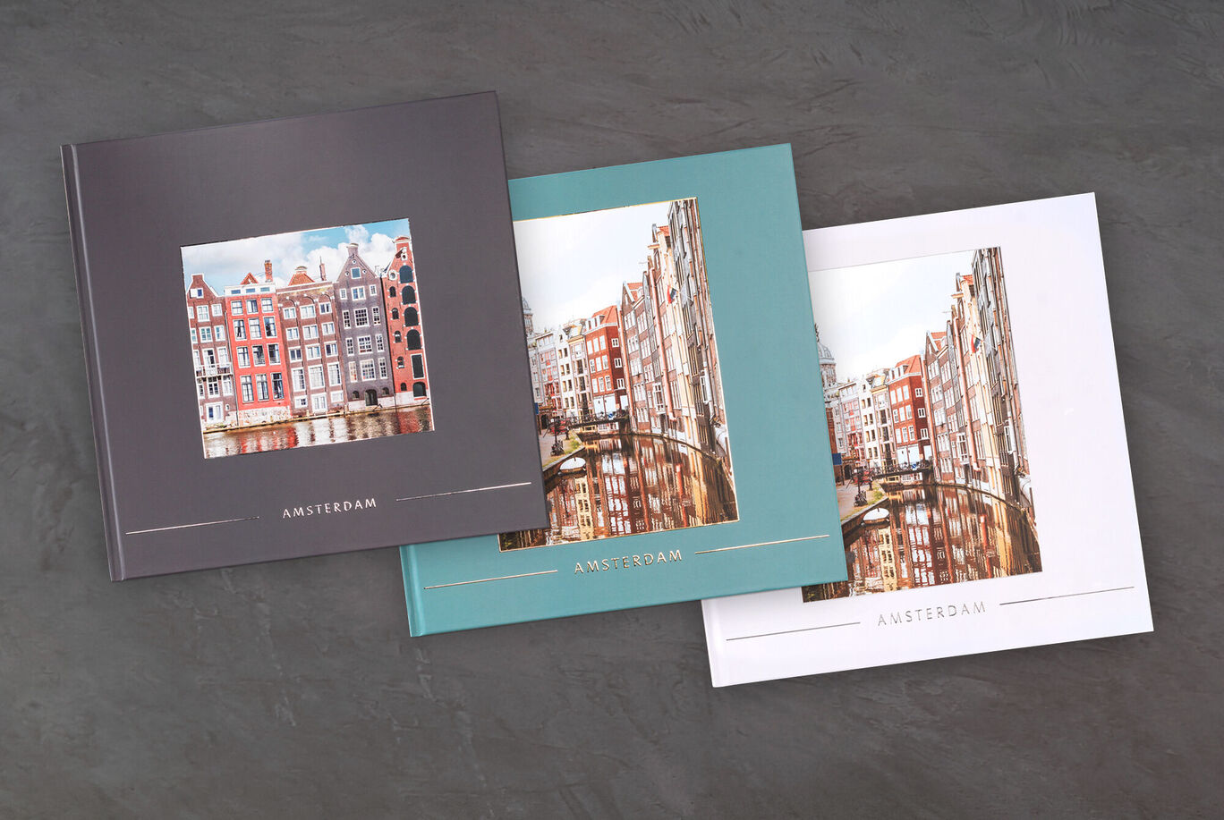 Trois livres photo CEWE différents avec des images d'Amsterdam, chacun avec un schéma de couleurs distinct.