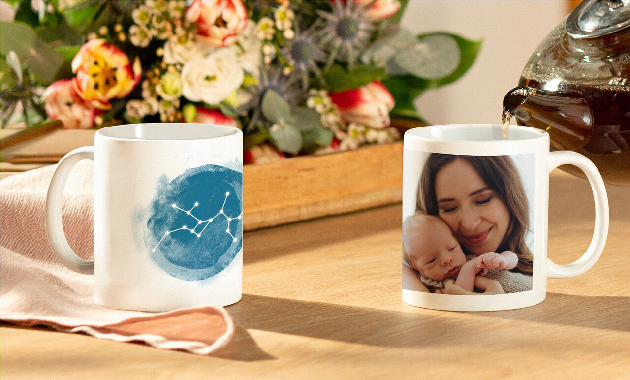 Deux tasses blanches sur une table en bois, l'une avec motif bleu, l'autre avec photo personnelle