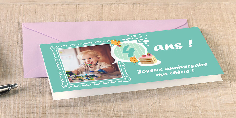 Un enfant joyeux peignant sur une table colorée. Des matériaux créatifs et un gâteau d'anniversaire sont sur la table.