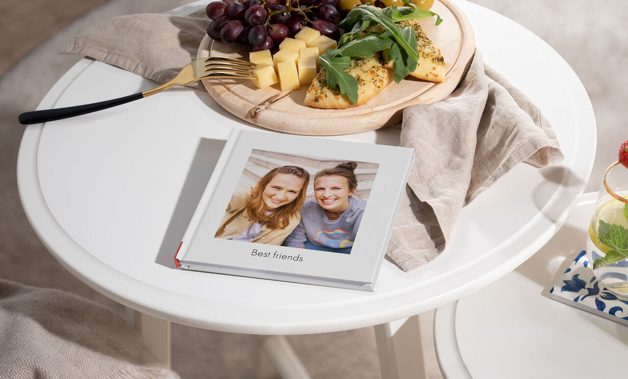 Un livre photo soigneusement conçu avec le titre 'Meilleurs amis' sur une table, entouré de fruits et d'en-cas.