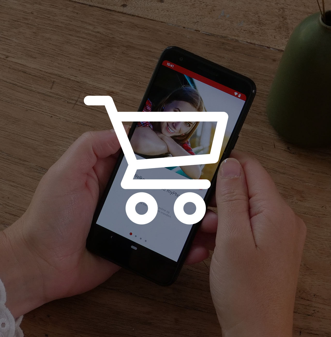 Des mains tiennent un smartphone avec une icône de panier d’achat.