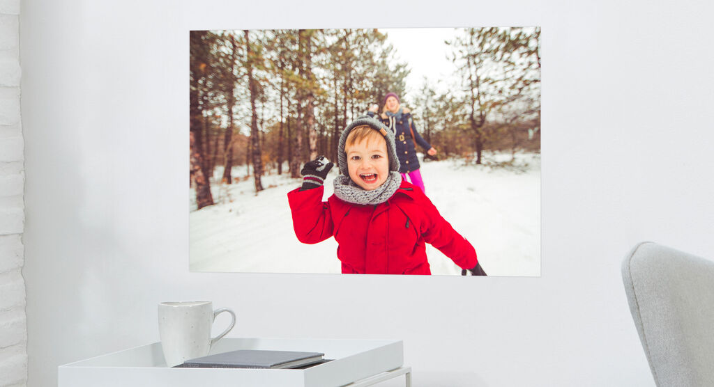 Deux enfants jouent joyeusement dans la neige, le soleil brille, des arbres en arrière-plan.