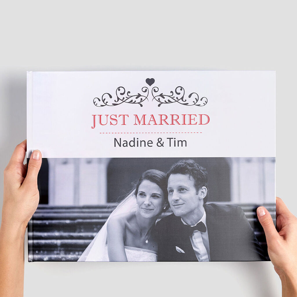 Mariés tenant un album photo CEWE intitulé 'Just Married'.