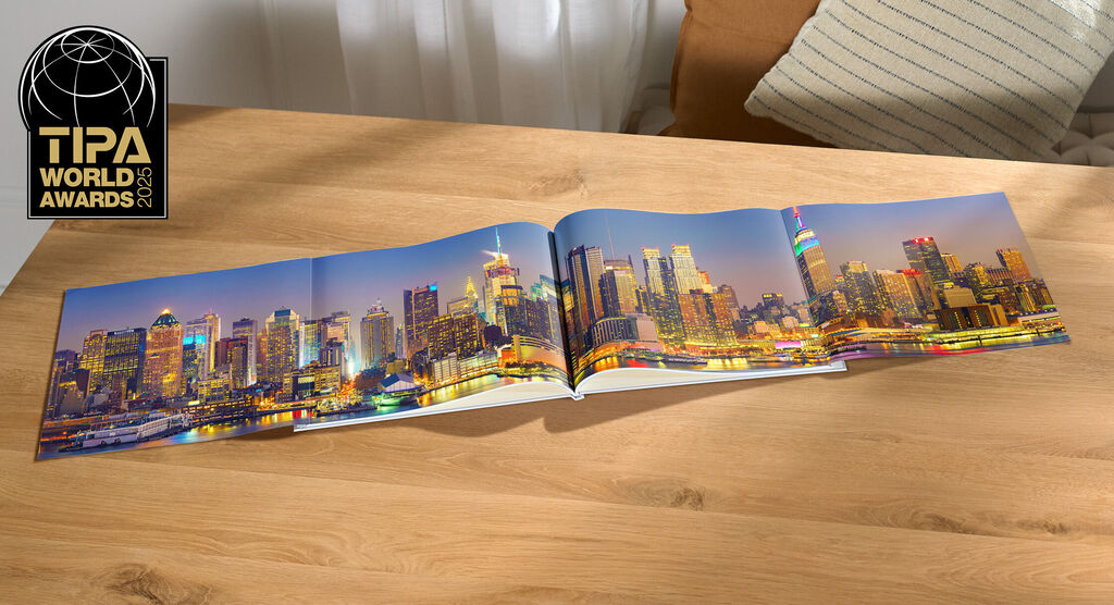 Livre photo CEWE avec une impressionnante photo de la skyline d'une ville de nuit sur une table