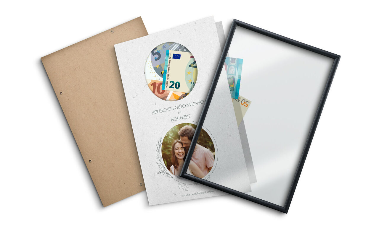 Deux livres photo CEWE ouverts avec des billets et un cadre.