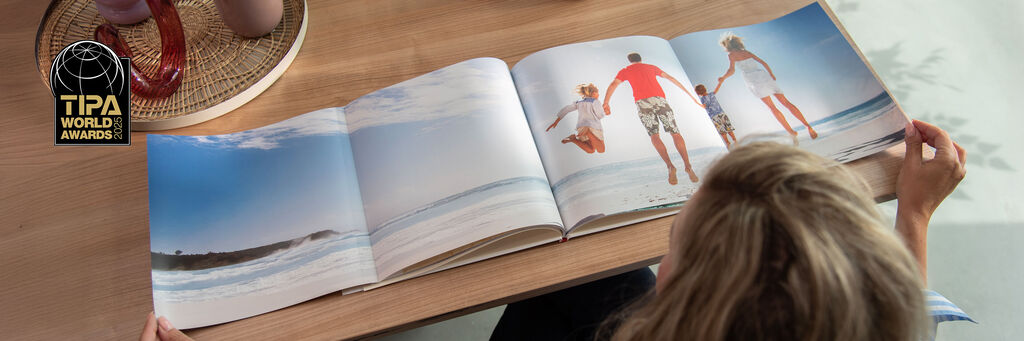 Une personne feuillette un livre photo ouvert avec des images de famille à la plage, dans un bel environnement.