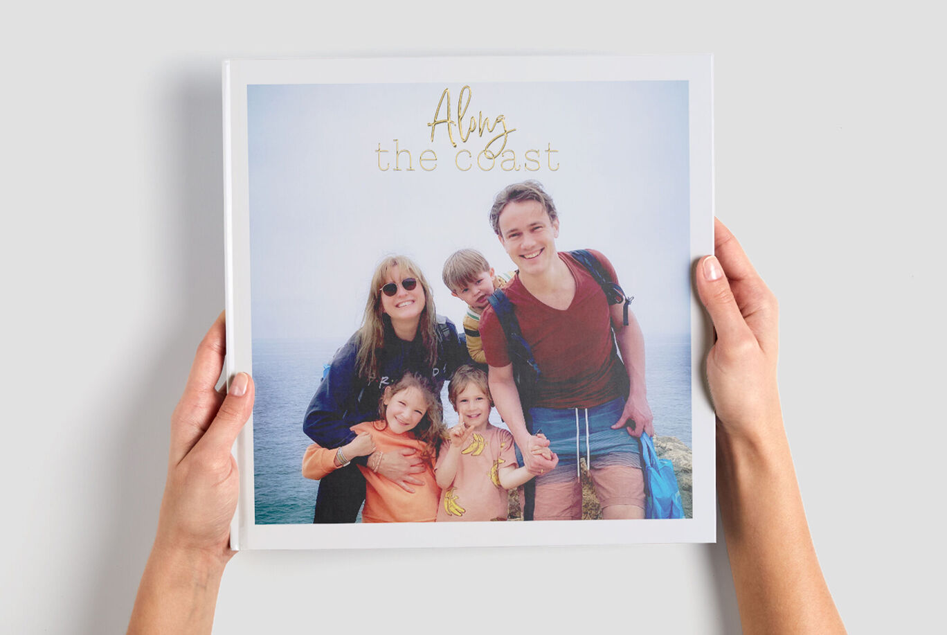 Un groupe de personnes tient un CEWE Livre Photo illustrant leurs vacances ensemble.