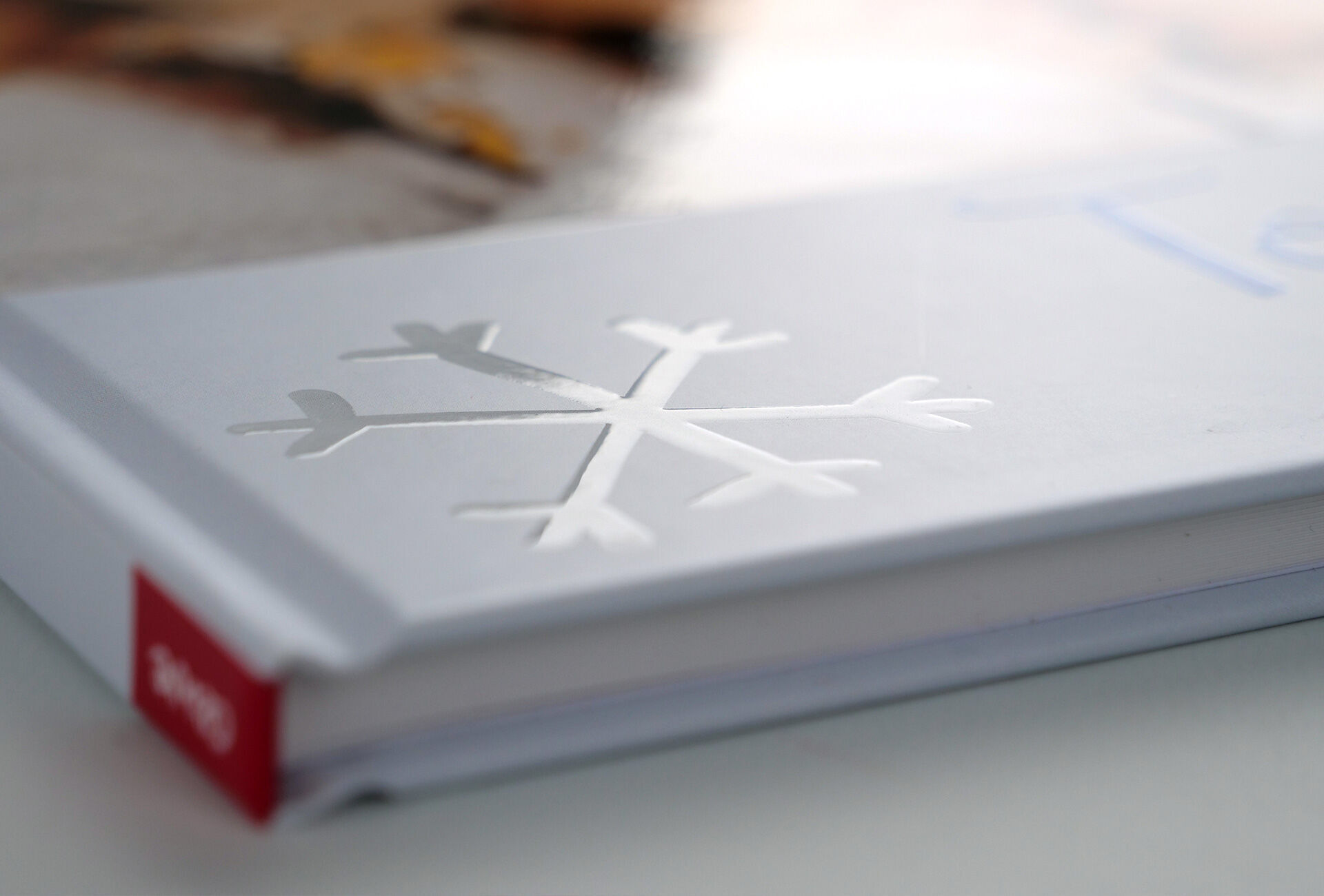 Un gros plan détaillé de la couverture d'un livre photo CEWE avec un flocon de neige schématique et une surface blanche élégante.