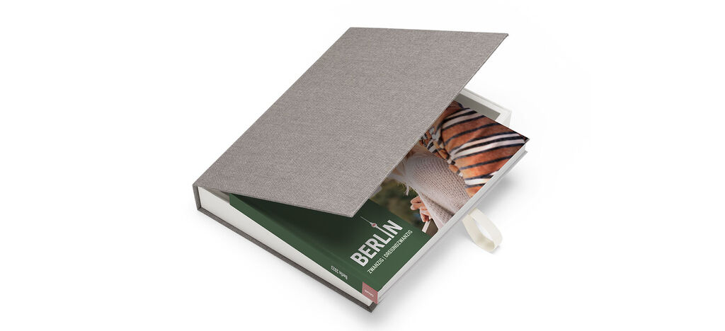 Un livre photo CEWE ouvert avec une page d'accueil verte et une image de Berlin.