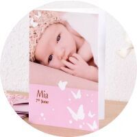 Un adorable livre photo CEWE montre un bébé avec un joli bandeau. Le nom Mia figure sur la couverture.