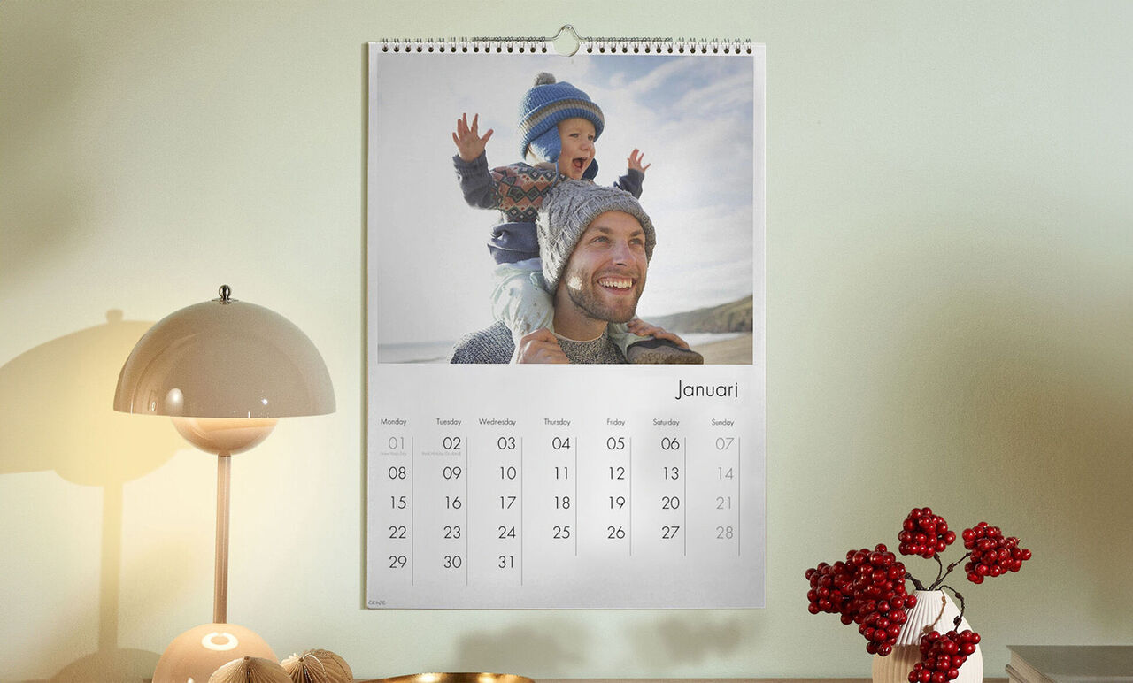 Un calendrier élégant montre un janvier joyeux avec un enfant en vêtements d'hiver assis sur un adulte.