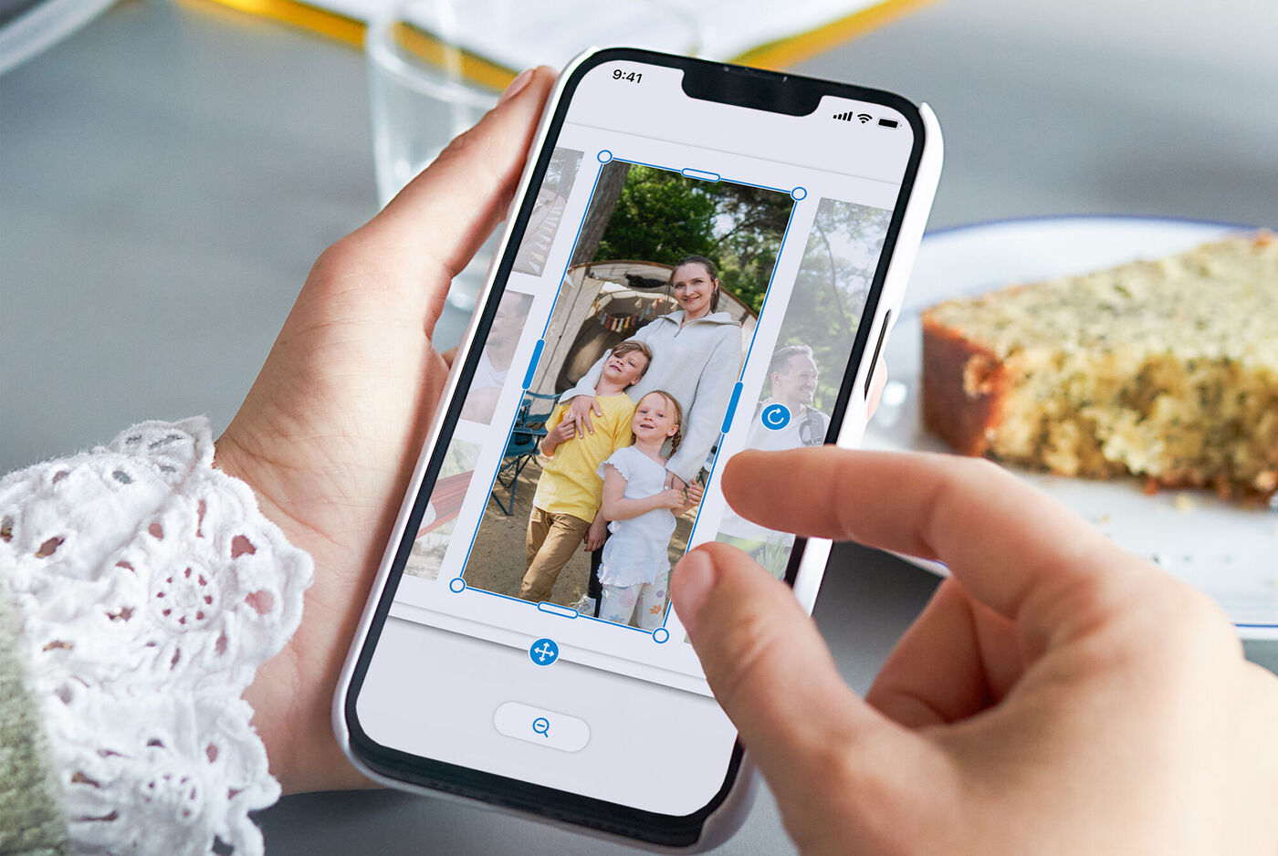 Un smartphone tenu en main avec une photo de famille. Une personne édite l'image. En arrière-plan, une tranche de gâteau savoureuse.