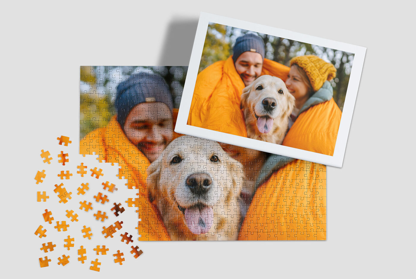 Un Golden Retriever sourit depuis un sac de couchage orange. En arrière-plan, un paysage d'automne coloré