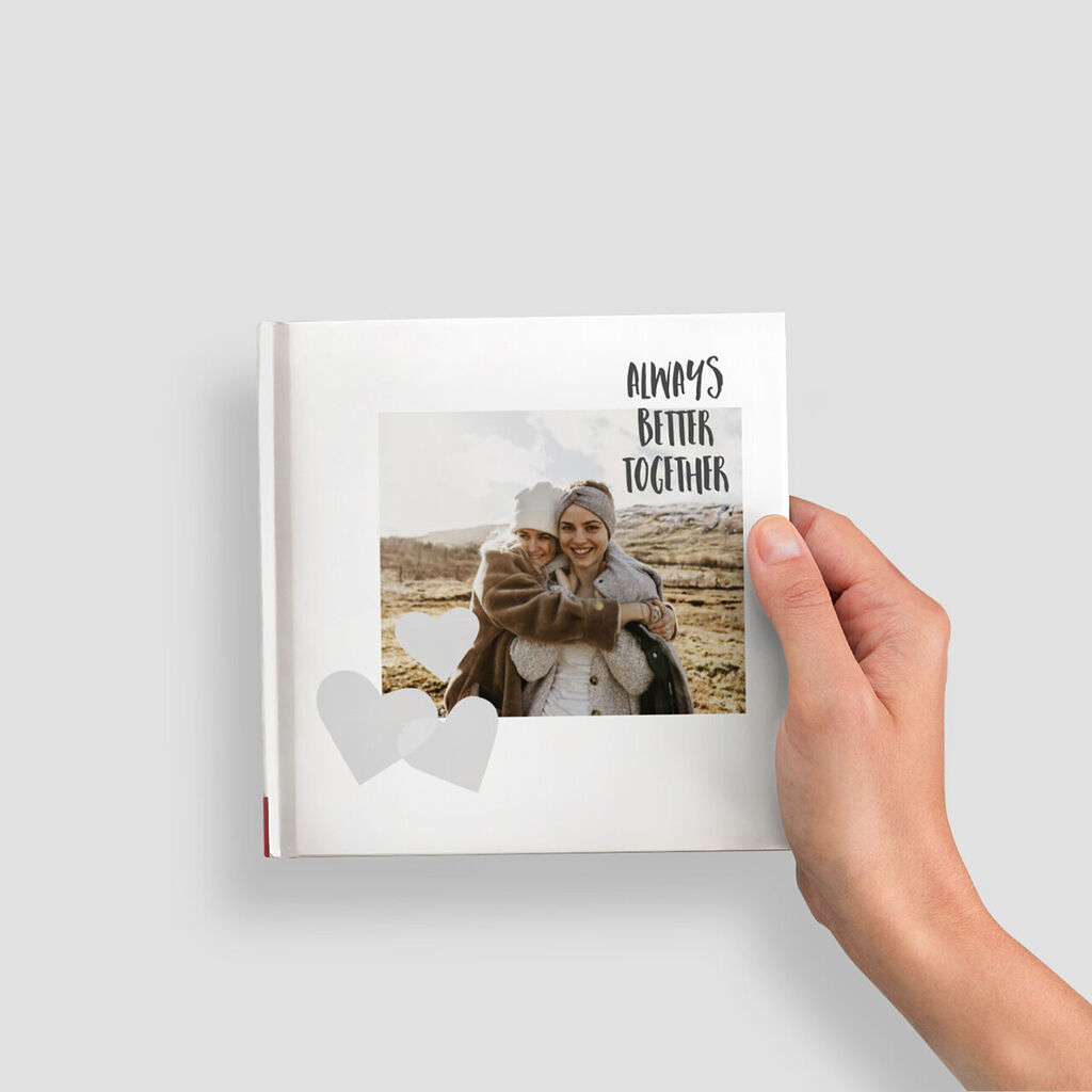 Une personne tient un livre photo CEWE avec une photo chaleureuse d'un couple.