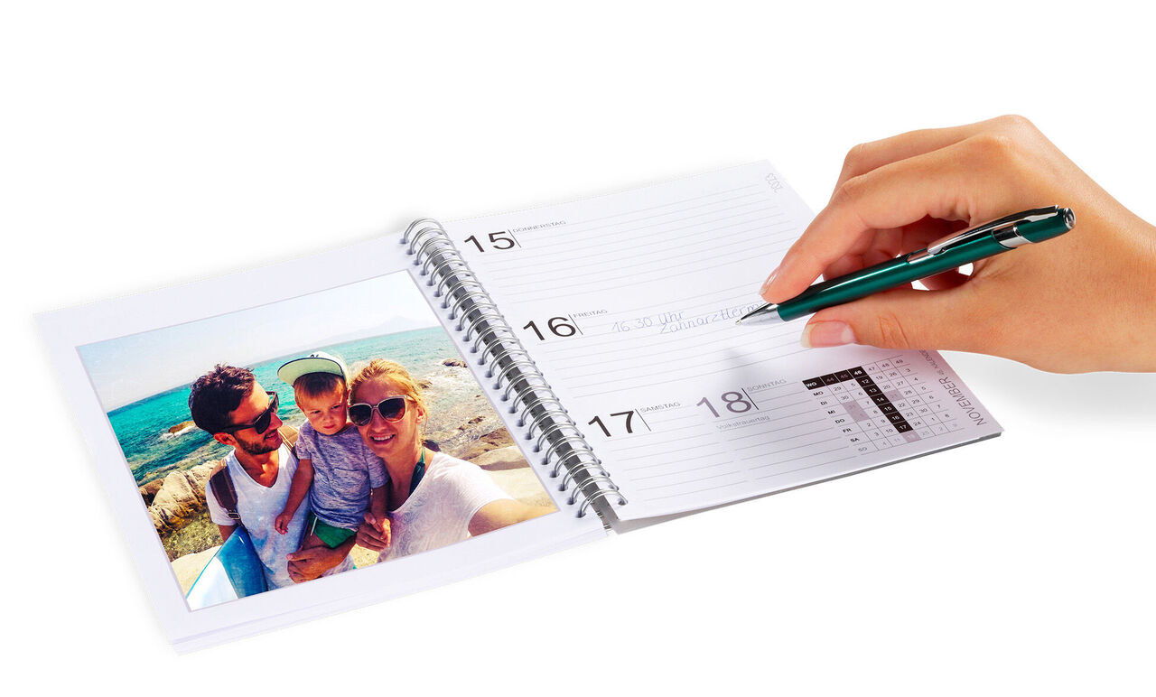 Une personne écrit dans un calendrier, avec une photo de personnes heureuses sur une page.