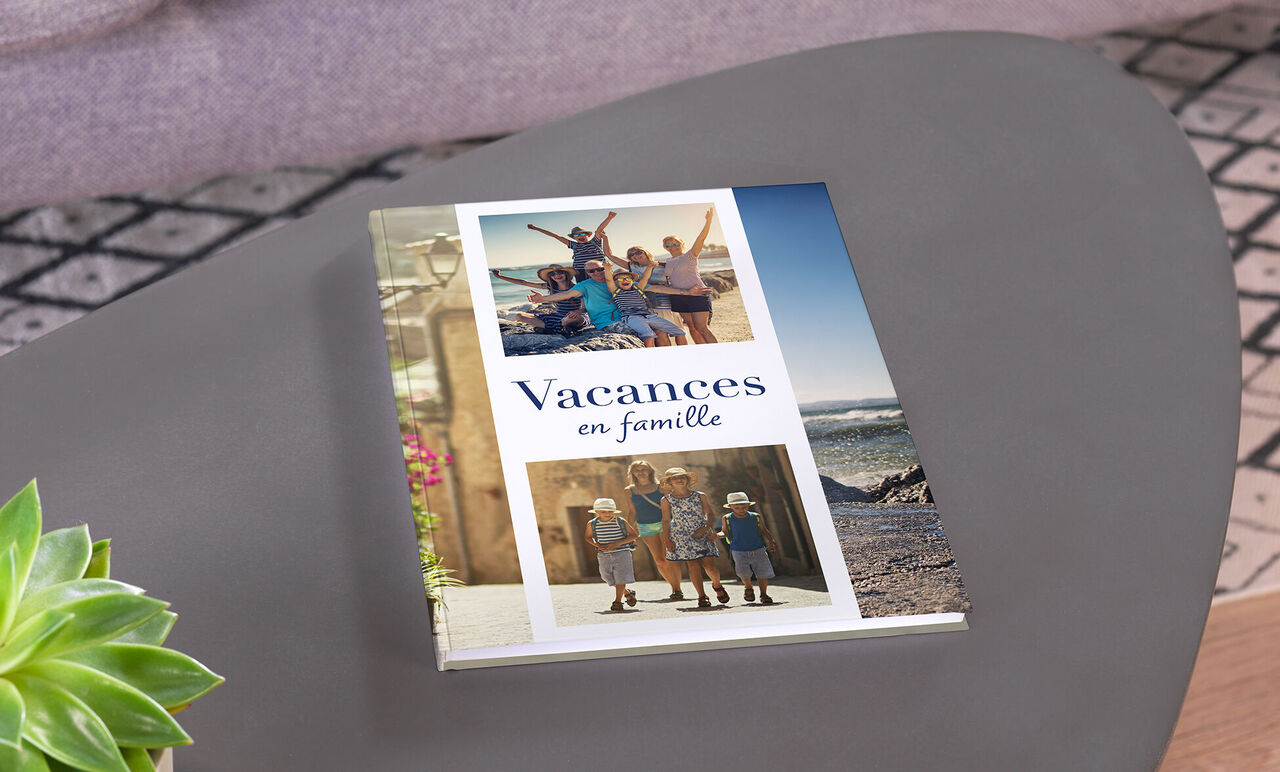 Un livre photo CEWE sur une table avec des photos de famille en vacances à la plage.