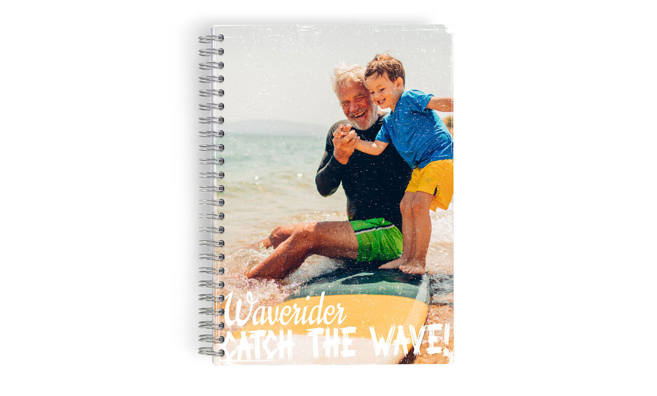 Un père avec son enfant à la plage, assis et jouant sur une planche de surf.