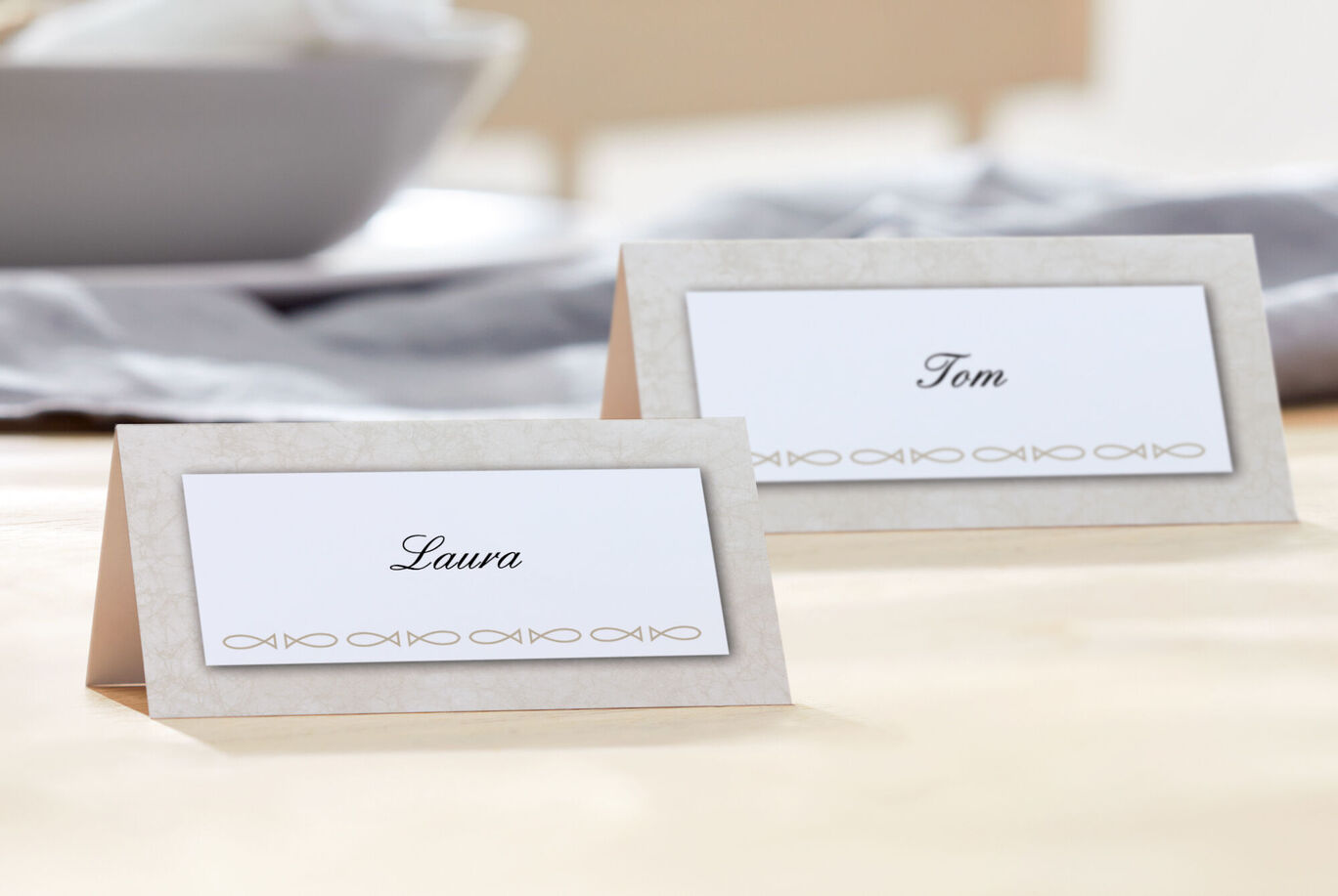 Deux cartes de table avec les noms Laura et Tom sur une table claire.