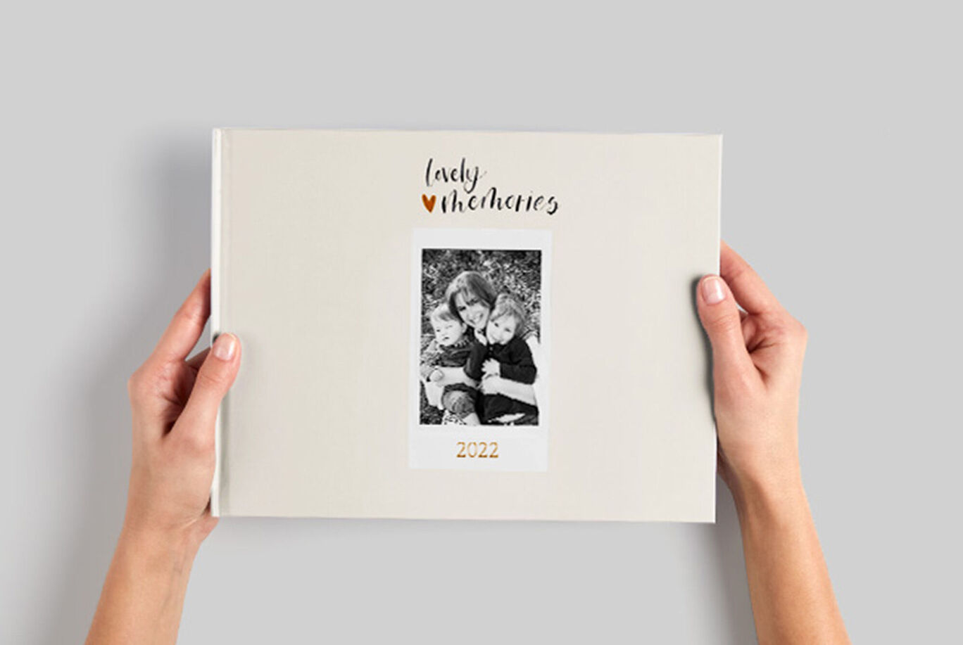 Une personne tient un CEWE FOTOBUCH avec une photo de famille sur la couverture. Fond neutre, texte 'lady' et '2022'.