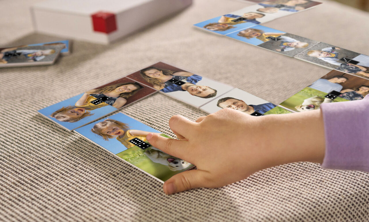 Un enfant joue avec des dominos personnalisés présentant des photos d'amis et de famille.