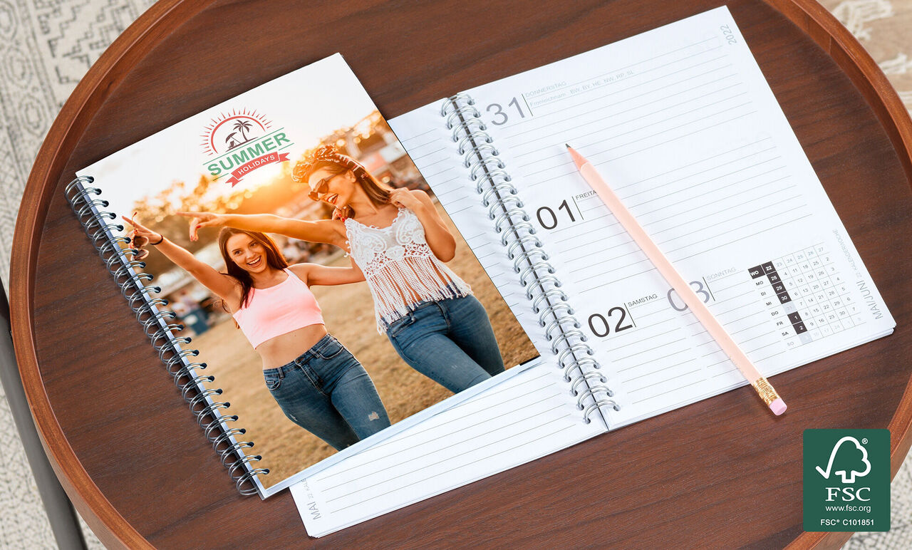 Deux femmes souriant heureuses devant un calendrier photo CEWE en été