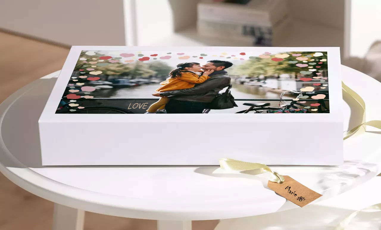 Un couple amoureux s'enlace sur une table avec une boîte cadeau au premier plan.