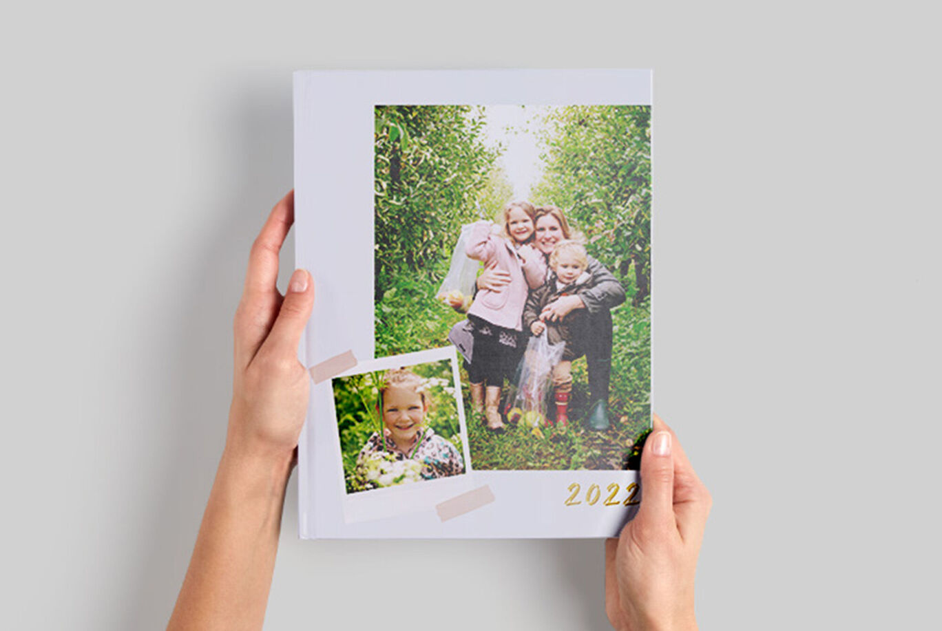 Iemand houdt een CEWE fotoboek vast met een familiefoto en een klein drankje.