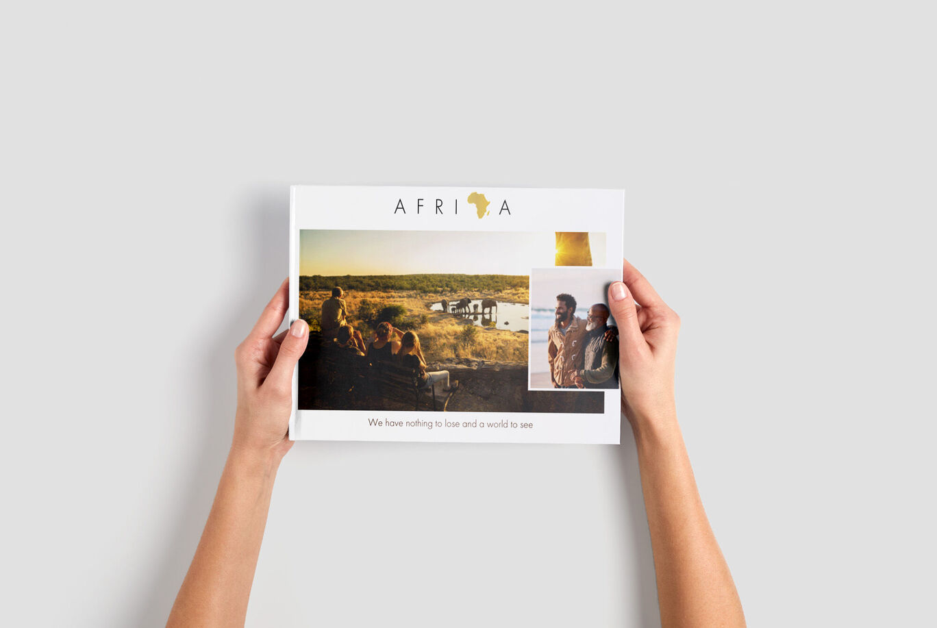 Handen houden een CEWE-fotoboek met een Afrika-thema en twee familiefoto's.
